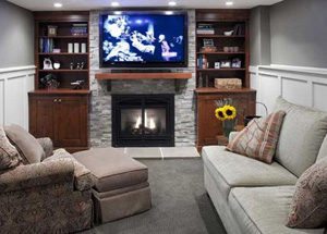 basement remodeling with giant screen wall mounted television, fireplace, and plush lounge chairs